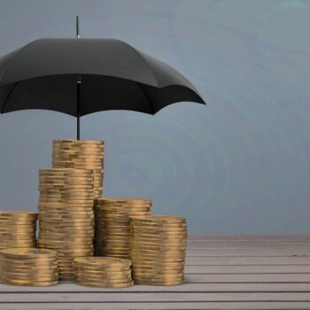 Monety pod parasolem jako symbol bezpieczeństwa finansów podczas inwestowania na forex