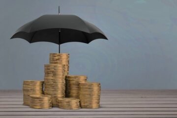 Monety pod parasolem jako symbol bezpieczeństwa finansów podczas inwestowania na forex
